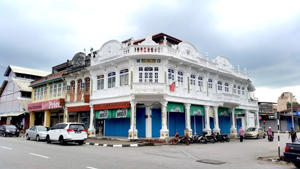 A colonial style building sits on the corner of two roads