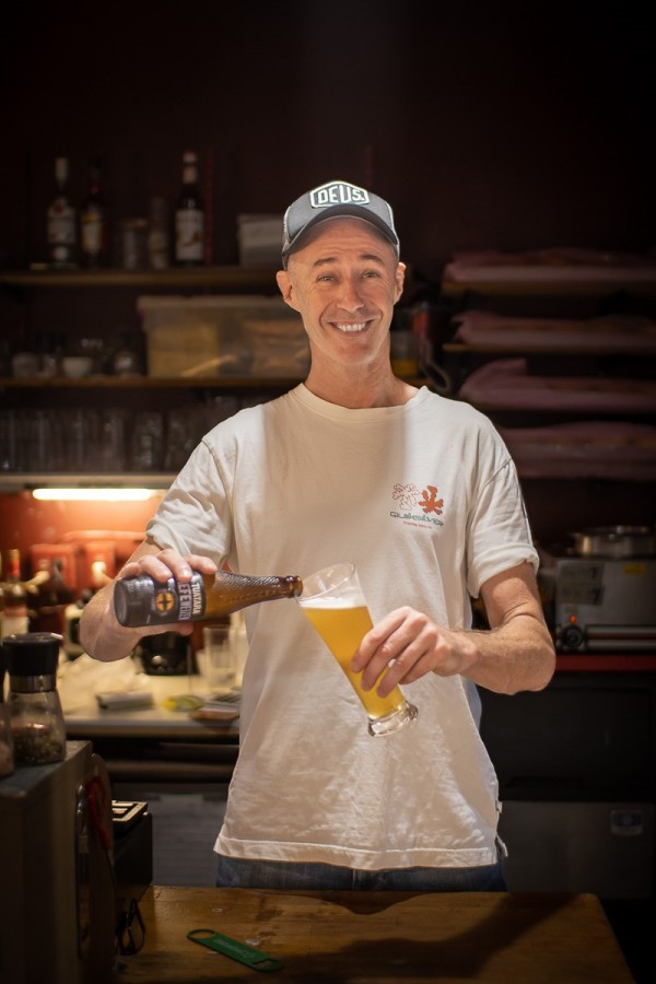 A man grins as he fills up a glass with beer from a bottle